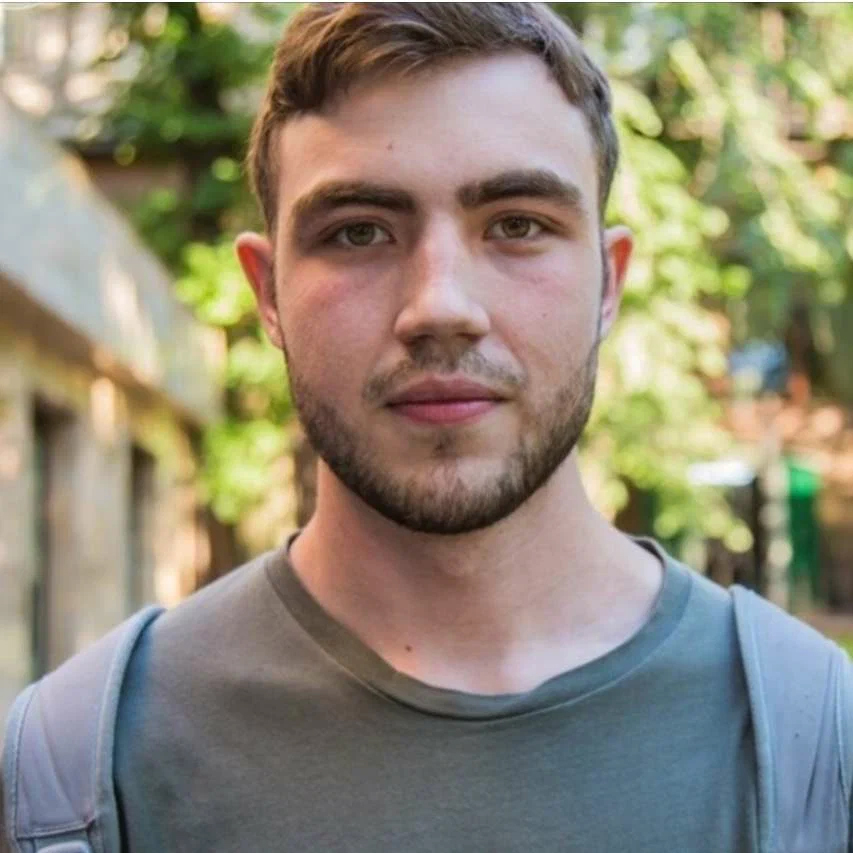 Portrait of a man wearing a grey shirt outdoors